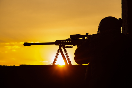 Army sniper with large-caliber sniper rifle seeking killing enemy. Silhouette on sky background. National security ensured, servicemen on guardの写真素材