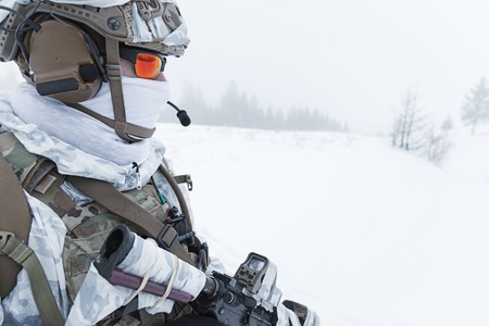 Winter arctic mountains warfare. Action in cold conditions. Trooper with weapons in forest somewhere...