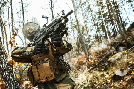 Norwegian Rapid reaction special forces FSK soldier firing in the forest. Field camo uniforms,...