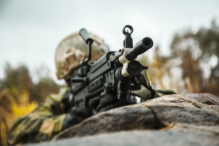 Norwegian Rapid reaction special forces FSK soldier firing in the forest. Field camo uniforms, combat helmet and eye-wear goggles are onの写真素材