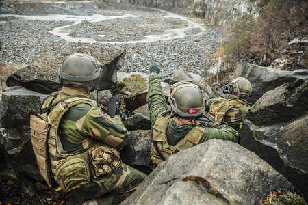 Patrol of norwegian Rapid reaction special forces FSK soldiers in field uniforms in ambush among the rocks guarding perimeter waiting enemyの写真素材