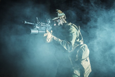 Image of soldier in the smoke moving in battle operation. Back light, cropped, toned and colorizedの写真素材