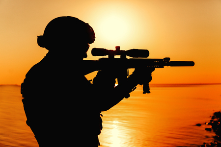 Army soldier with rifle orange sunset silhouetteの写真素材