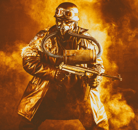 Futuristic  soldier in fire and smoke gas mask and steel helmet with  handgun