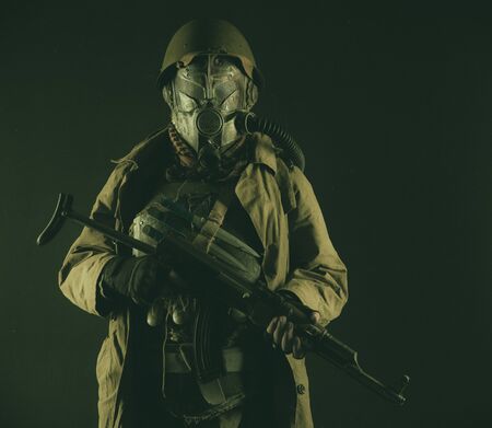 Nuclear post-apocalypse survivor, alternative history nazi soldier or partisan in wool field cap, face gas mask, glasses and handmade armor, with rifle gun studio shootの写真素材