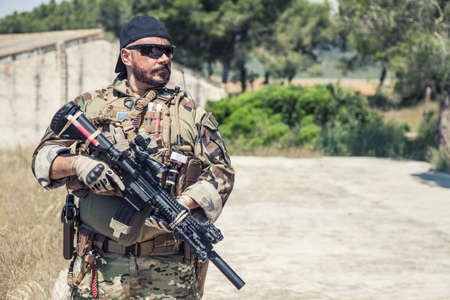 Navy SEALs fighter in ballistic goggles, equipped military ammunition and body armour, holding...