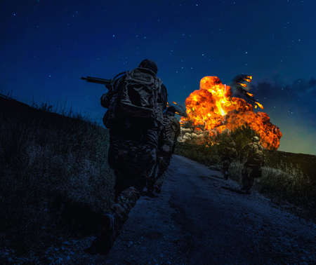 Army soldiers loaded with ammunition, running on battlefield at night. Commando team rushing on...