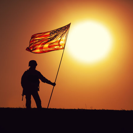 Silhouette of US army infantry soldier, United States Marines Corps fighter standing on sunset horizon with waving USA national flag. Soldiers heroism and victory in battle, honoring of fallen heroesの写真素材