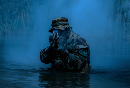 A bearded soldier performs a surveillance task in the water, walking through a swamp, surrounded by night fog, rifle at the ready for imminent threats, colorized toned shotの写真素材