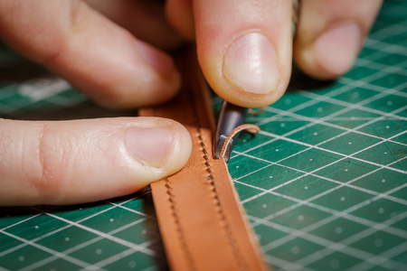 A person working as an artisan in his leather workshop removes the chamferの写真素材