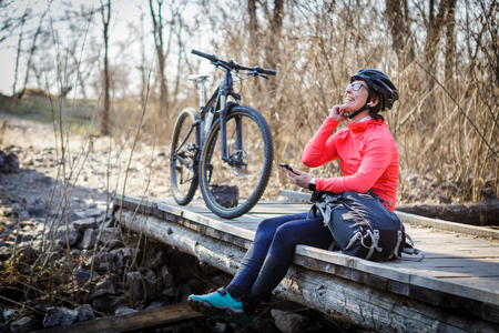 female cyclist listens to music while resting on in the forestの写真素材