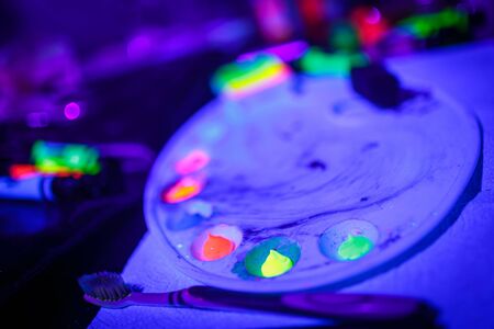 Multicolored UV fluorescent powder and paints on a paletteの写真素材