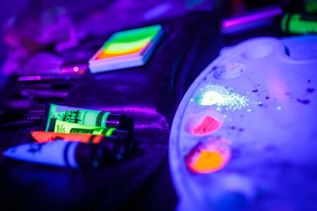 Multicolored UV fluorescent powder and paints on a paletteの写真素材