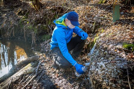Ecologist taking water samples from a natural source in protective glovesの写真素材