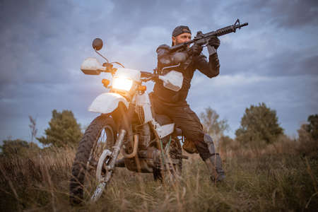 a man with a gun is aiming while sitting on a motorcycleの写真素材