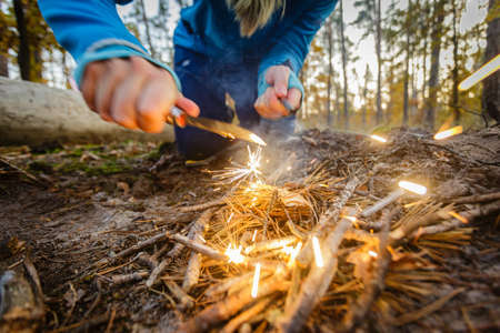Man outdoors makeing fire by flint. Front view. Flying sparks.の写真素材