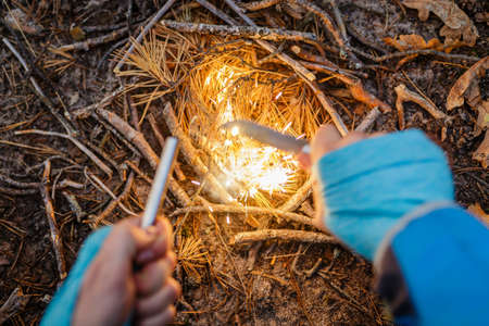 Man outdoors makeing fire by flint. View from above. Flying sparks.の写真素材