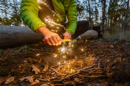 Man outdoors makeing fire by flint. Front view. Flying sparks.の写真素材