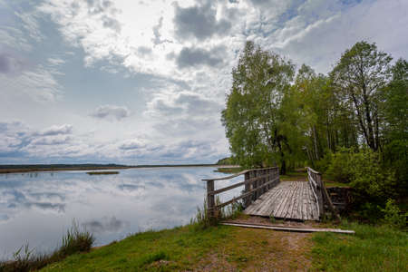 Beautiful landscape with a lake and a bridge. Cloudy weather. A bridge over a canal that flows into Lake Didovo in Ukraine.の写真素材
