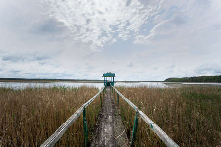 Beautiful landscape with a lake and a bridge. Cloudy weather.の写真素材