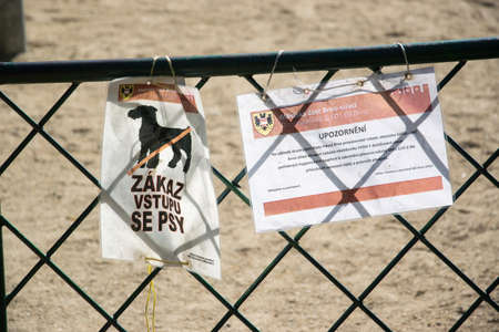 Wrinkled signs prohibiting dogs from entering the playground, hung by a rope on the fenceのeditorial素材