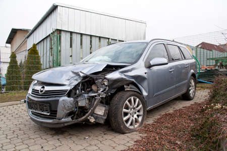 Broken car in a winter car accident on slippery snow. View of the broken hood, fender, punctured wheel and completely destroyed light.のeditorial素材