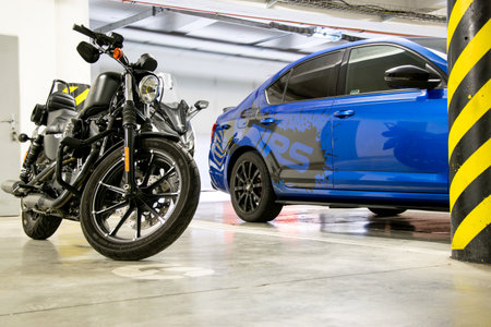 BRNO, CZECH REPUBLIC - NOVEMBER 17, 2021: Blue sports car and black motorbike parked in the underground garage. The car has stickers made of black glossy foil on its side.のeditorial素材