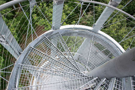 Round staircase of a high steel lookout tower. The stairs are hung on the main supporting column....