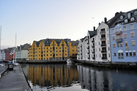 Old colorful houses on the waterfront in Alesund, Norway in the evening at sunset.のeditorial素材