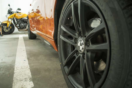 Close-up on a black wheel of an orange sports car standing in a garage.