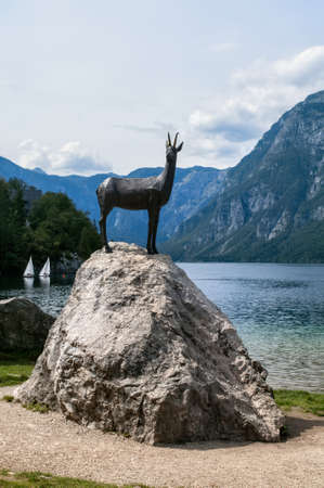 Lake Bohinj in Slovenia. Statue of a chamois standing on a rock on the beach by the water.の写真素材