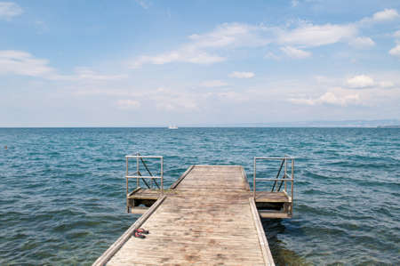 A wooden pier with a railing and a ladder into the water in the summer floats on the sea.の写真素材