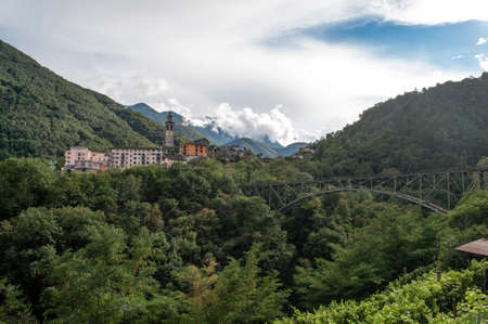 A small village in the Swiss mountains with an iron railway bridge over the valley.の写真素材