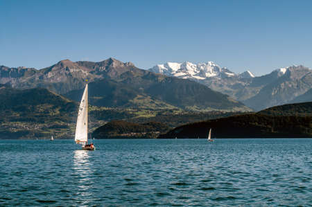 A lake in Switzerland surrounded by high mountains. Boats and sailboats sail across the lake.のeditorial素材