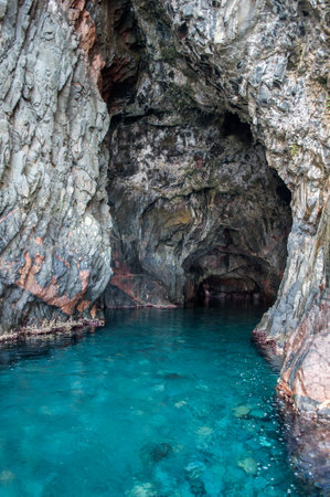 A cave hidden in a cliff above sea level full of clear blue water. Coastline on the island of Corsica in France in Europe.の写真素材
