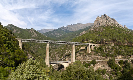 A steel high railway bridge between two mountains on the island of Corsica in France. A mountain road for trains in the south of Europe.の写真素材