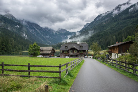 Jagersee, Austria - Access road to wooden hotels by the lake in the cloudy mountains.のeditorial素材