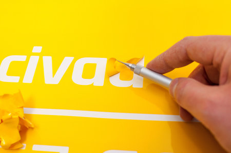 Close-up of a man's hand making a car sticker from yellow foilの写真素材