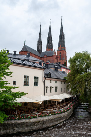 Uppsala Cathedral, Sweden - church towers with waterfront and restaurant above the river.のeditorial素材