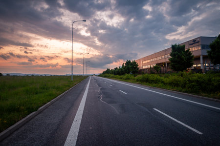 Road with lamps near an industrial warehouse in the evening at sunset.の写真素材