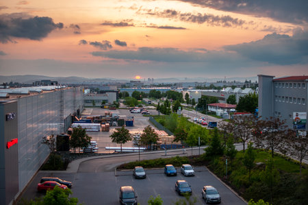 Brno, Czech Republic - 23 May 2023: Evening sunset over the city and an industrial area with warehouses and a parking lot.のeditorial素材
