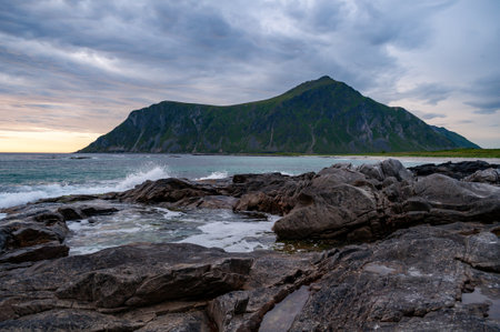 Sunset into the sea with rocks and splashing waves - Skagen, Lofoten, Norway.の写真素材