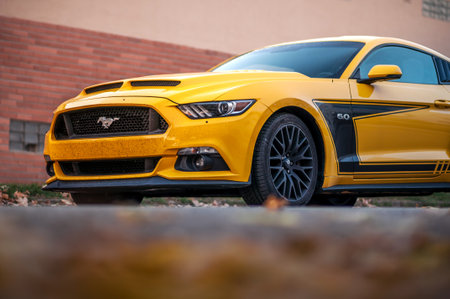 Brno, Czech Republic - October 25, 2023: Yellow muscle car Ford Mustang is parked on the street in the evening in autumn.のeditorial素材