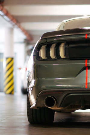 Brno, Czech Republic - November 1, 2023: A dark green Ford Mustang with gray and red foil fast stripes is parked in a garage.のeditorial素材