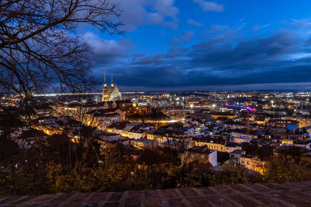 Brno, Czech Republic - December 21, 2023: Night city panorama with illuminated streets and cathedral with tall towers in the center of the city. Evening street with street lights.のeditorial素材