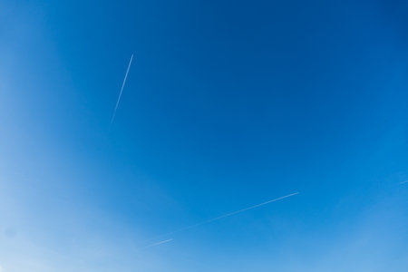 Two airplanes with white contrail in blue sky.の写真素材