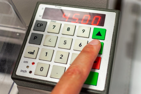 The hand of a worker who controls the machine with a push-button keyboard with a display.の写真素材