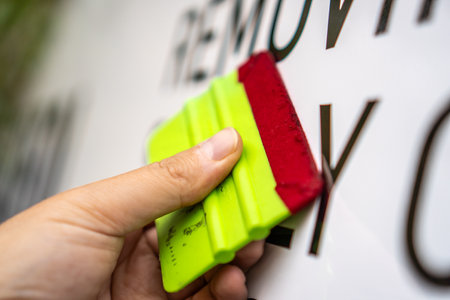 A person installing stickers on a car. Applying the sticker with a plastic spatula.の写真素材