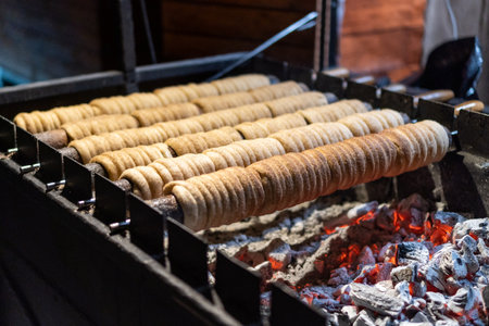 Traditional trdelnik made of dough is baked on hot coals. Sweetness at an outdoor snack stand on the...