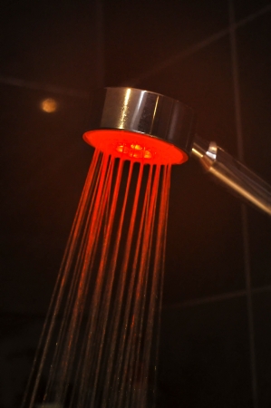 A modern shower head in a bathroom with differing colours being displayed の写真素材